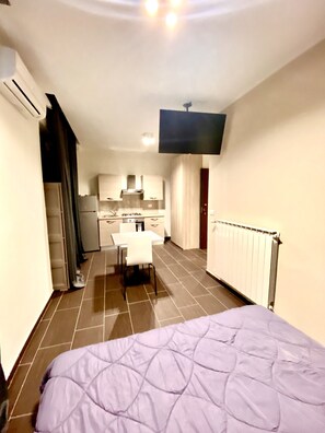 A compact hotel room with a bed, a kitchenette, and a TV mounted on the wall. - Hermoso Housing HH Valenza (Valenza)