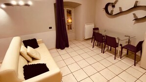 Una sala de estar con sofá, sillas, una mesa y una ventana con cortinas.
