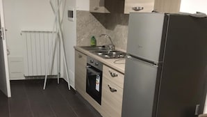 Una cocina compacta equipada con refrigerador, horno y pileta.
