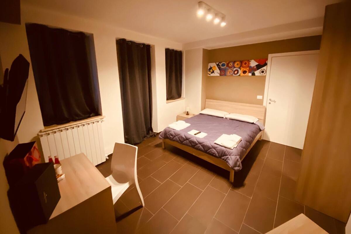 Ein Schlafzimmer mit Bett, Stuhl, Schreibtisch, Heizkörper und Tür.