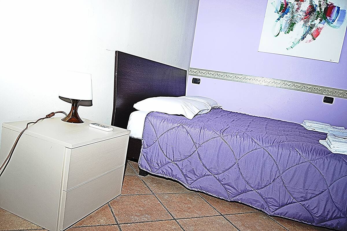 Ein Zimmer mit einem Bett, einem Nachttisch und einer Wand mit dekorativer Bordüre.