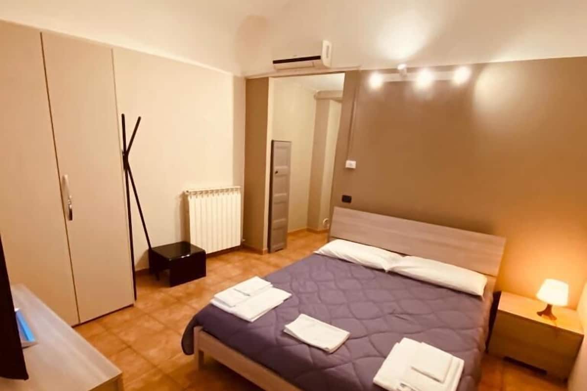 Ein ordentlich eingerichtetes Schlafzimmer mit Bett, Nachttisch und Kleiderschrank.