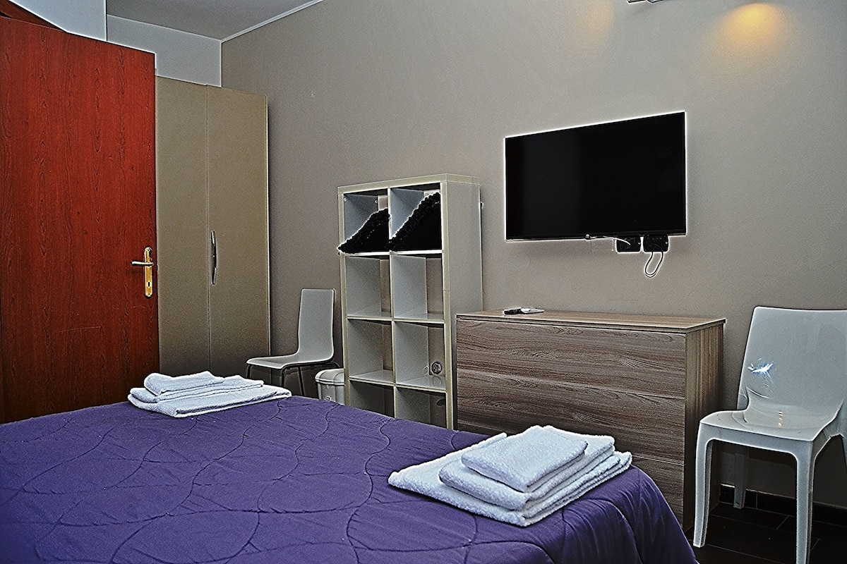 Ein Hotelzimmer mit Bett, Kleiderschrank, Fernseher und Schreibtisch.