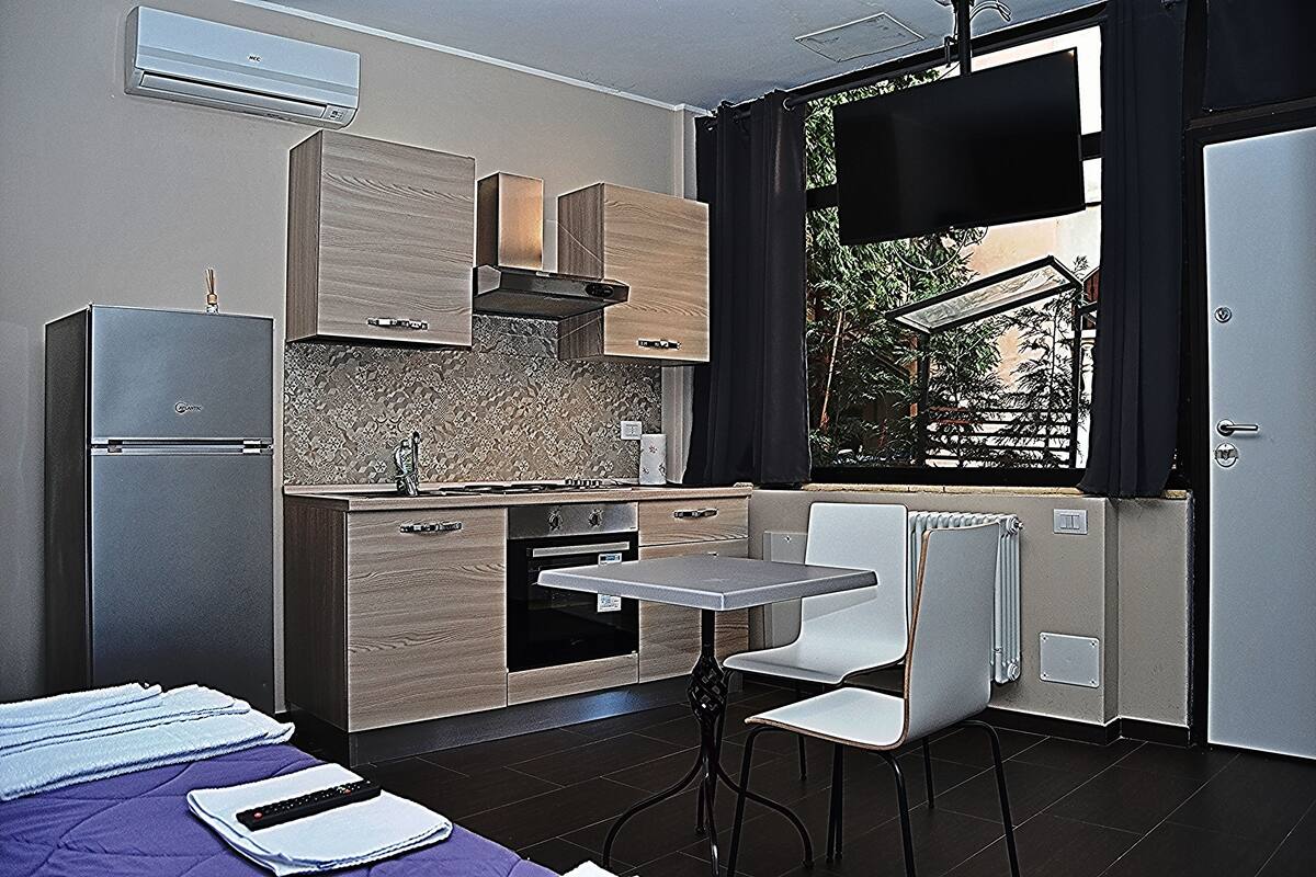 Eine kleine Küche mit Kühlschrank, Backofen und einem Essplatz mit Stühlen.