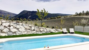 Une piscine avec un mur en pierre et une clôture blanche.