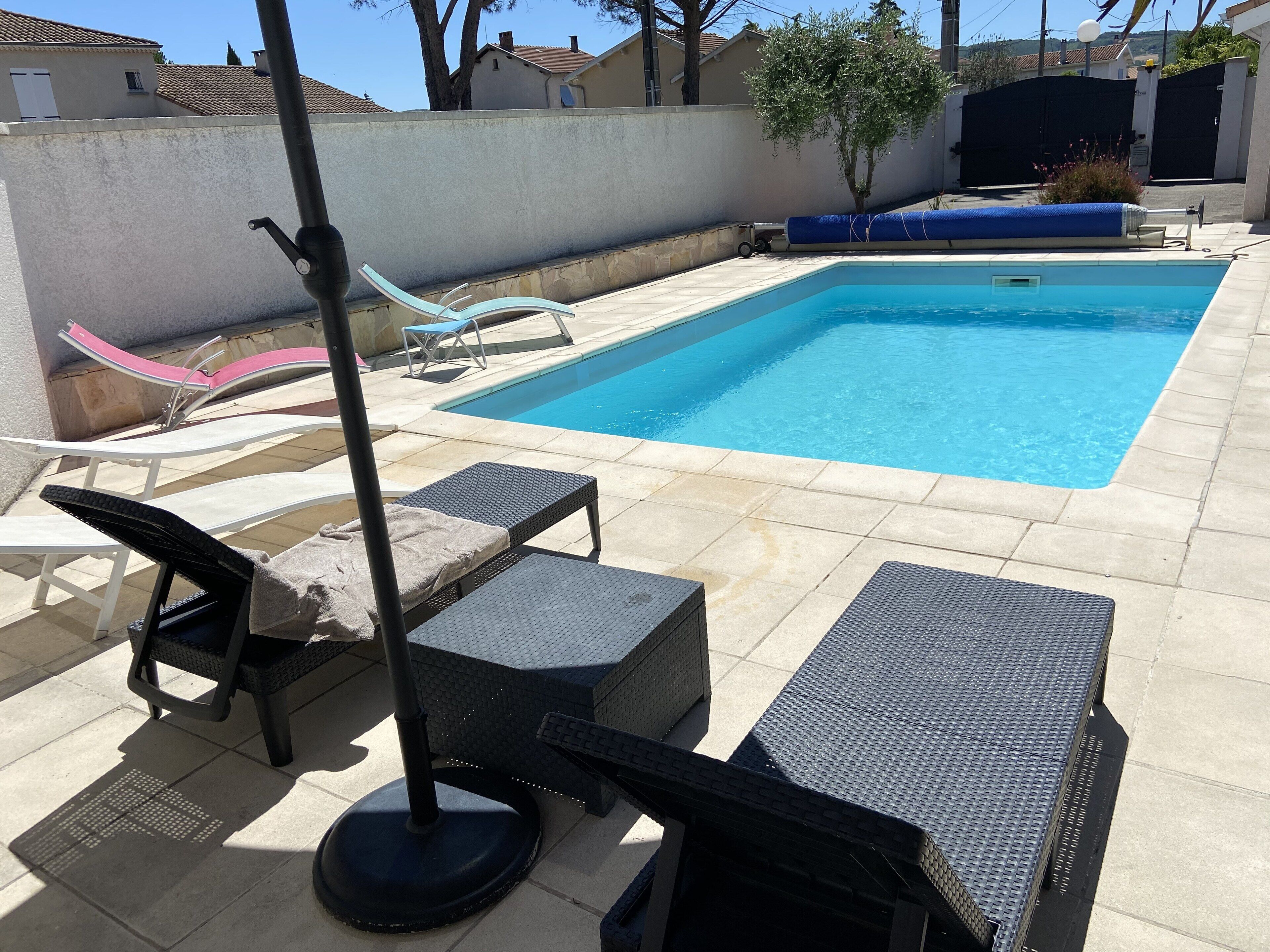 A swimming pool with lounge chairs and a sunshade.