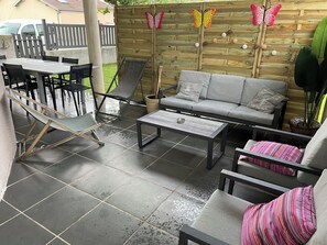 Un espace extérieur aménagé avec une table, des chaises, un canapé et un hamac.