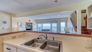 A kitchen with a large window overlooking the beach, a wooden staircase, and a view of the ocean. - Periwinkle - Oceanfront 3 BR, 2.5 BA home in Surf City!  Dog Friendly! (Surf City)