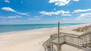 Ein Strand mit einer Holzpromenade, die zum Wasser führt, bewölkter Himmel und ruhiges Meer.