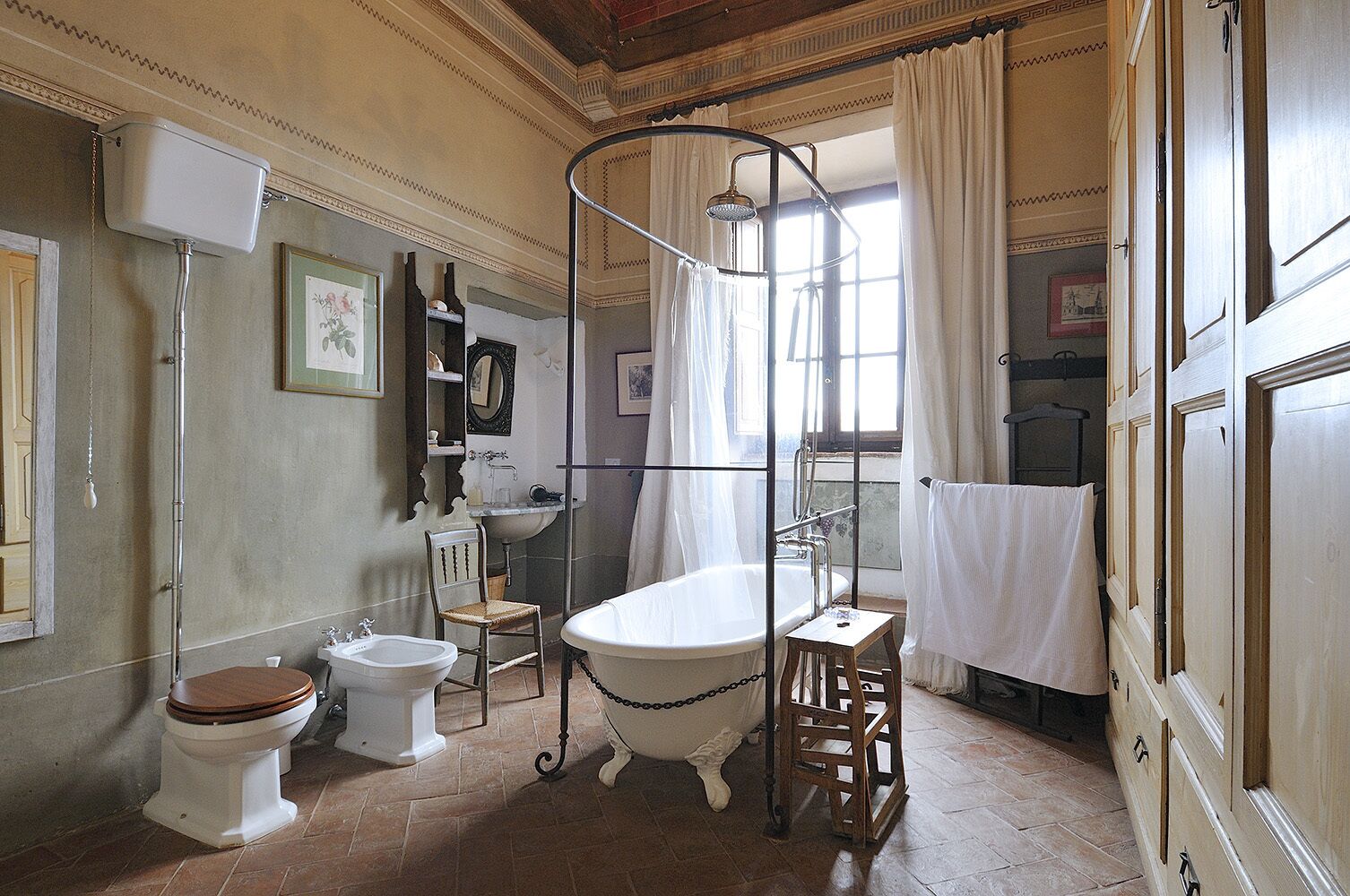 Une salle de bain de style ancien, avec une baignoire sur pieds, un lavabo sur colonne et des toilettes.