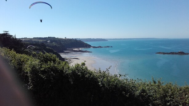 A coastal landscape with a beach, cliffs, and a person paragliding. - HOUSE NEAR ROSAIRES BEACH (Plérin)