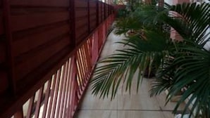 A covered corridor with a tiled floor, red railings, and potted plants. - Starscape Hotel (Ndola)