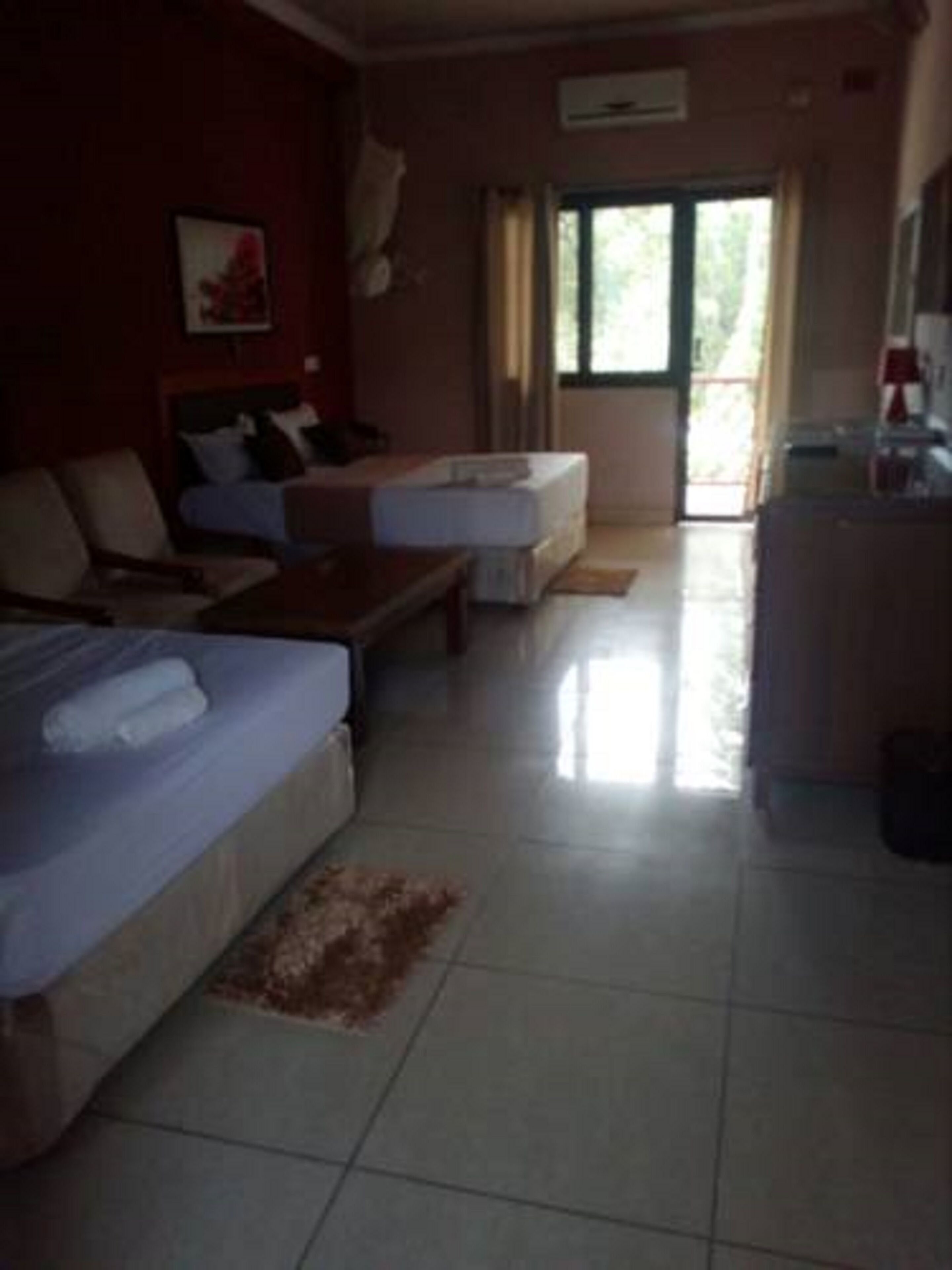 A hotel room with a bed, a sofa, a small table, and a window.