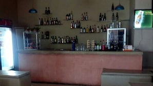 A bar area with a counter, shelves of bottles, and a television screen. - Starscape Hotel (Ndola)