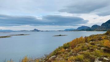 Paisagem costeira com um lago calmo, terreno rochoso e vegetação escassa.