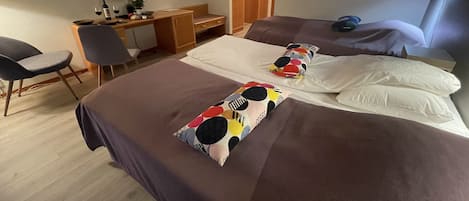 Una habitación de hotel con dos camas, un escritorio, una silla, un televisor y un espejo.