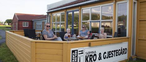 A yellow outdoor seating area with a sign for 'Sommna Kro & Gjestegård' offering catering services.