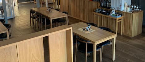 A restaurant with wooden tables and chairs, a bar area, and hanging spherical light fixtures.