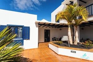 Une villa moderne dotée d’un patio, d’un espace salon extérieur et d’un palmier.