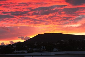 A sunset over a mountain with a silhouette of a town below. - Apartment 3 Small block of 6 apartments, a stones through from Marina Rubicon (Yaiza)