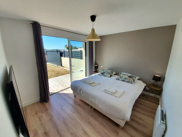 A bedroom with a bed, a TV, a ceiling light, and a view of the outdoors. - The Villa des Marins Pêcheurs, 8 people, Jacuzzi, Spa (Sibiril)