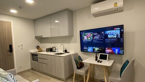 A modern kitchen with a built-in island, a dining area with a table and chairs, and a flat-screen TV mounted on the wall.