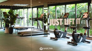 A gym with exercise equipment, large windows, and indoor plants.