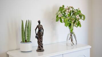 Een witte kast met een beeld en twee planten in potten.