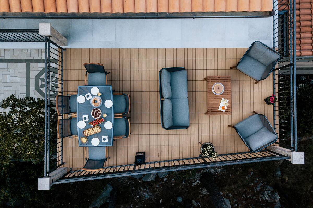 Une terrasse extérieure avec une table et des chaises, un canapé et une petite table agrémentée d’un objet décoratif.