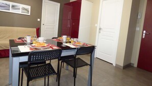 A dining area with a table set for two, chairs, and a red cabinet.