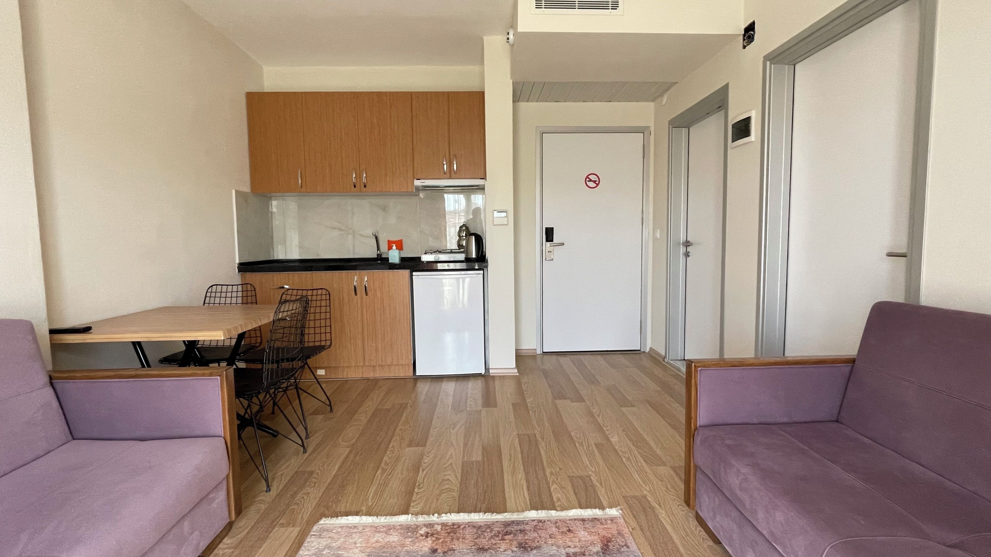 Een compacte woonruimte met een kitchenette, een eethoek en een zithoek.