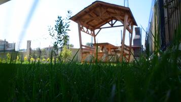 Un jardín de madera en un área con césped, con un edificio al fondo.