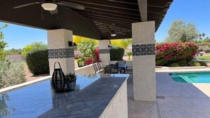 A covered outdoor pool area with a marble countertop, seating, and potted plants. - Incredibly spacious Gathering place, Private Pickleball Court, Sleeps 14, (Scottsdale)