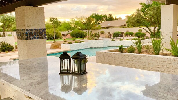 An outdoor bar area with a marble countertop, two stools, and two lanterns. - Incredibly spacious Gathering place, Private Pickleball Court, Sleeps 14, (Scottsdale)