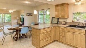 Una cocina moderna con armarios de madera, una isla grande y una zona de comedor con sillas.