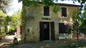 Un edificio rustico con facciata consunta, una porta nera e un piccolo finestrino.