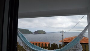 Un hamac dans une pièce offrant une vue sur la mer et les îles lointaines.