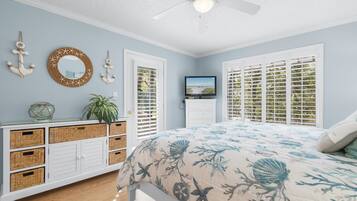 A bedroom with a bed, a dresser, a ceiling fan, and a window with blinds.