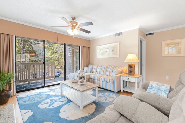 A living room with a sofa, a coffee table, a lamp, and a ceiling fan.