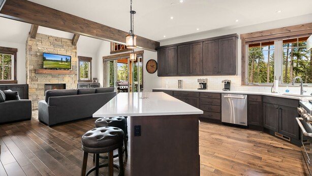 A modern kitchen with a large island, dark wood cabinets, and a stone fireplace. - Big Home with LOW RATES! In the Heart of Suncadia Resort | Hot Tub | WiFi (Cle Elum)