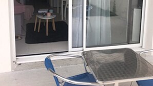Een kamer met een schuifglasdeur die uitkomt op een balkon met een tafel en stoelen.