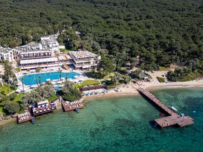 An aerial view of a resort with a large swimming pool, beach, and pier. - DoubleTree by Hilton Bodrum Işıl Club Resort (Bodrum)