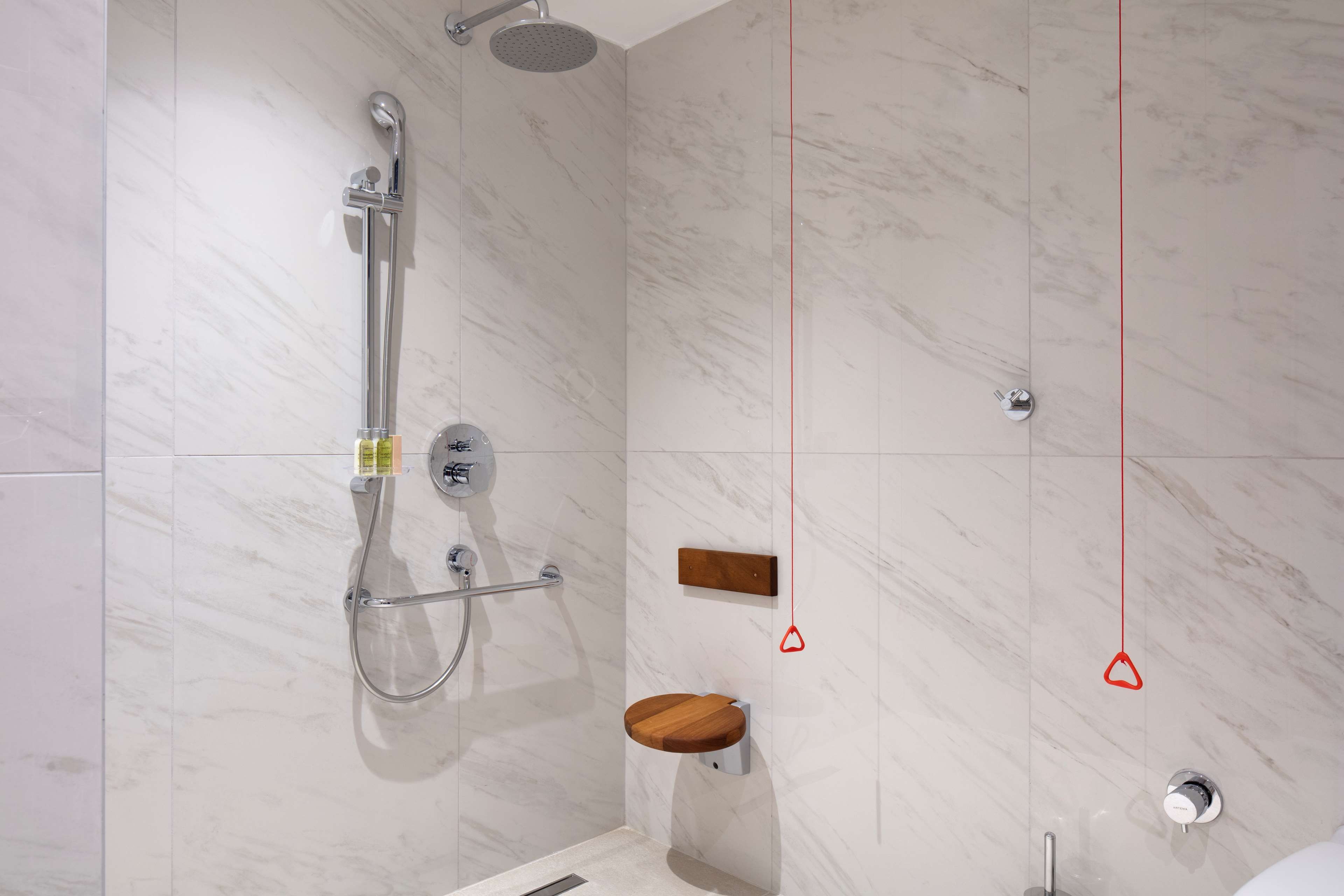 Une douche moderne dotée d’un pommeau de douche à main et d’un robinet mural.