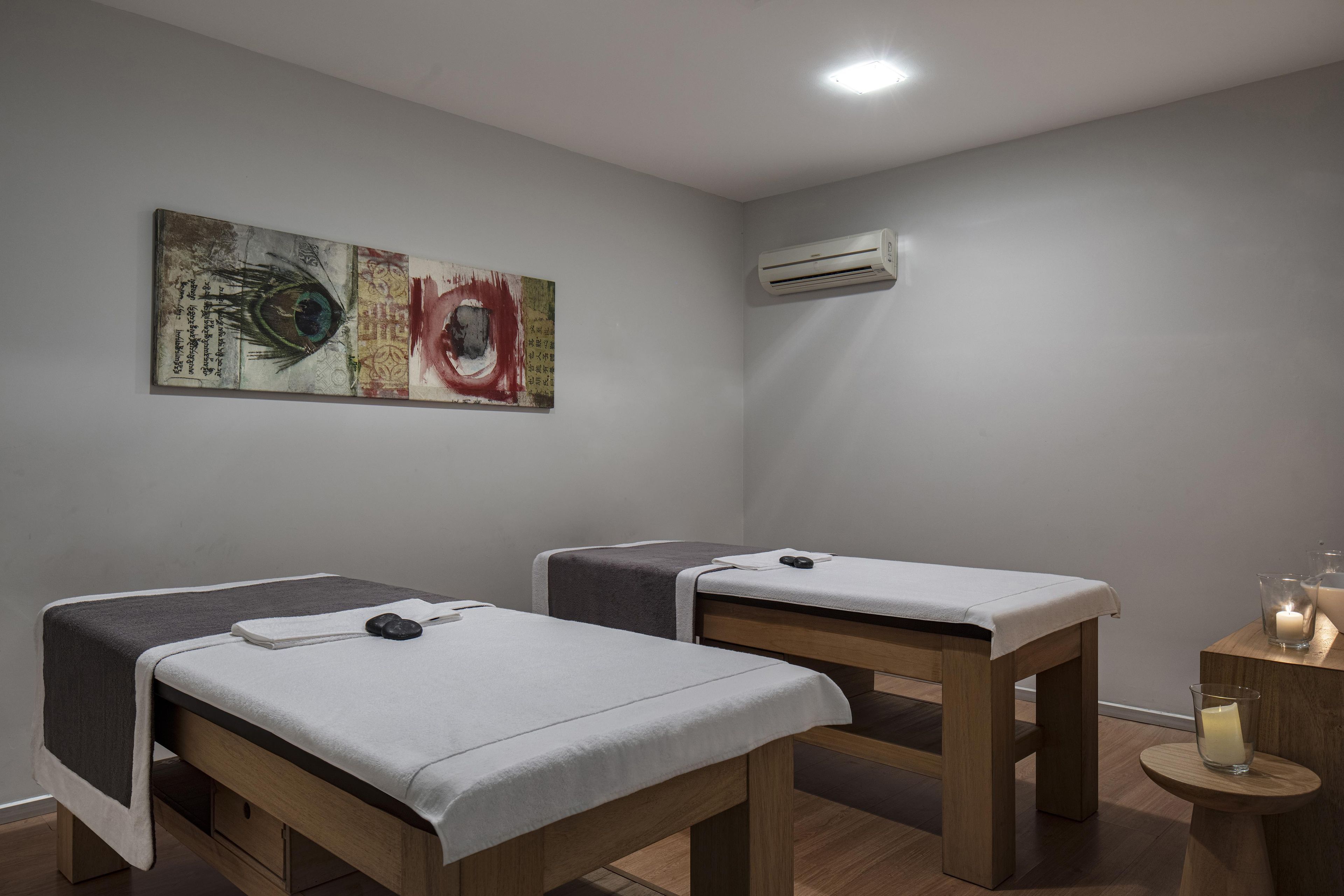 Una habitación con dos camas de madera, aire acondicionado instalado en la pared y un cuadro.