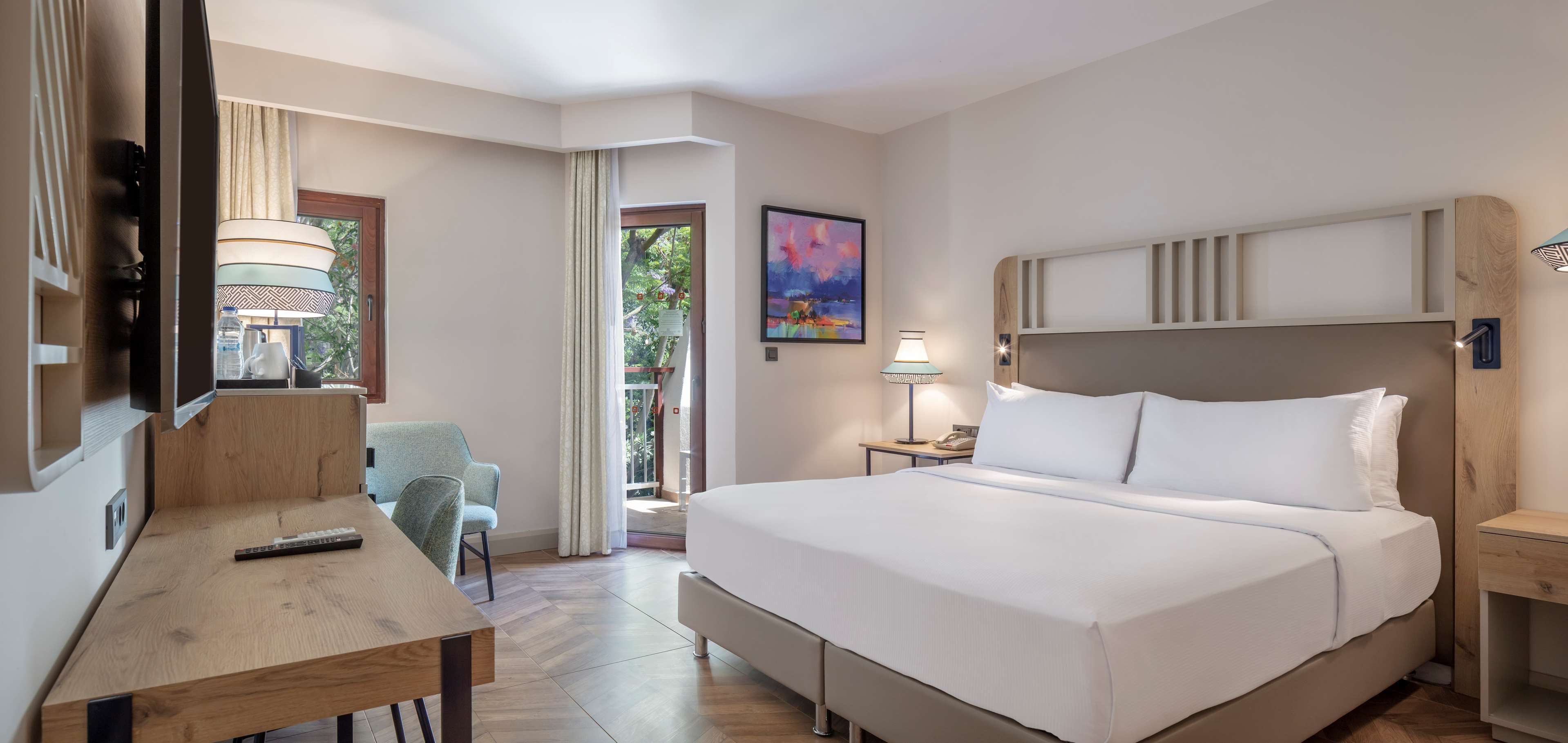 Ein Hotelzimmer mit Bett, Nachttisch, Lampe, Stuhl und einem Schreibtisch mit Fernbedienung.