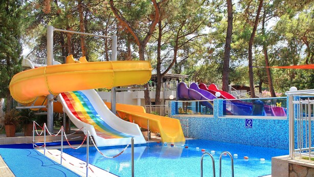 A swimming pool with multiple slides and a blue mosaic pool edge. - DoubleTree by Hilton Bodrum Işıl Club Ultra All Inclusive Resort (Bodrum)