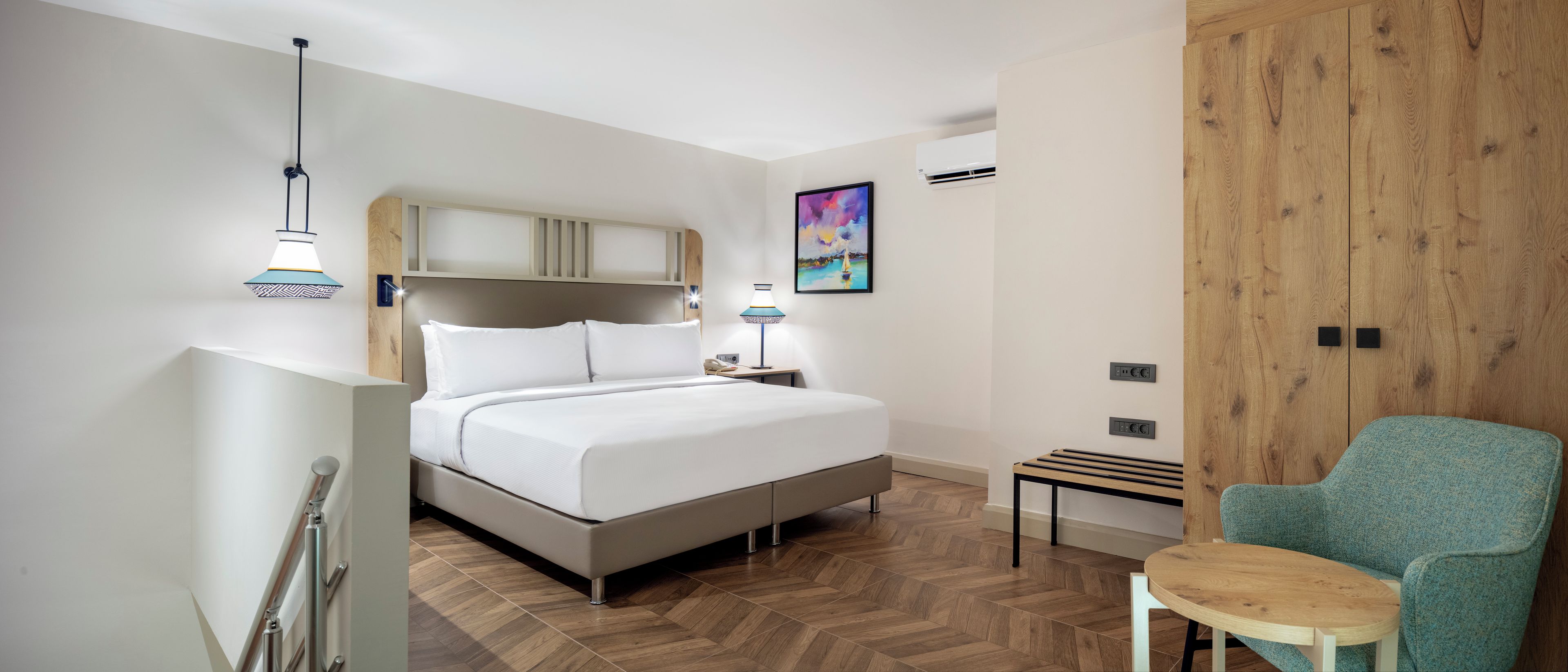 Una habitación de hotel moderna con cama, mesita de noche, lámpara y una silla.