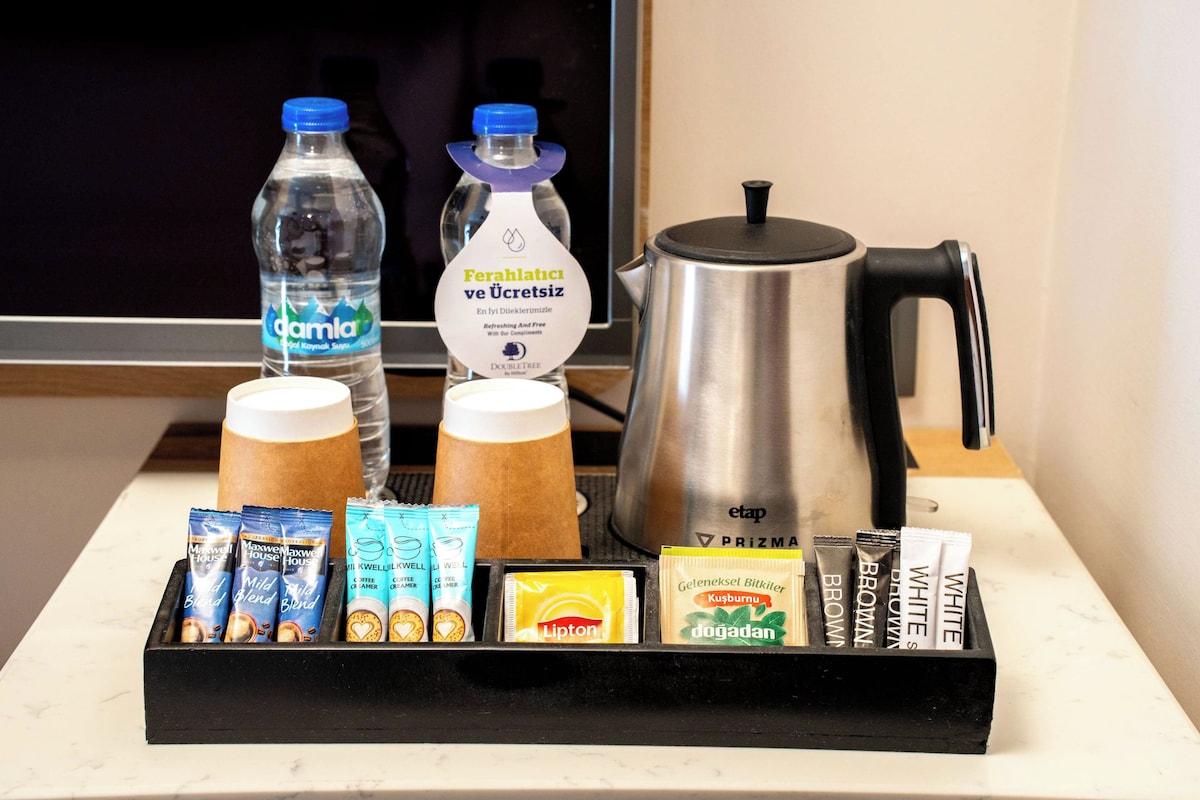 Bandeja de desayuno con agua embotellada, café, té y diferentes aperitivos envasados.