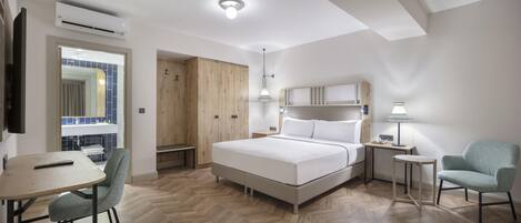 A hotel room with a bed, a desk, a chair, a wardrobe, and a window.