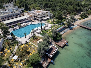 An aerial view of a resort with a large swimming pool, multiple deck areas, and a beach. - DoubleTree by Hilton Bodrum Işıl Club Resort (Bodrum)